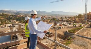 Arquitectos revisando planos en una obra de construcción de viviendas en Granada con vistas a Sierra Nevada.